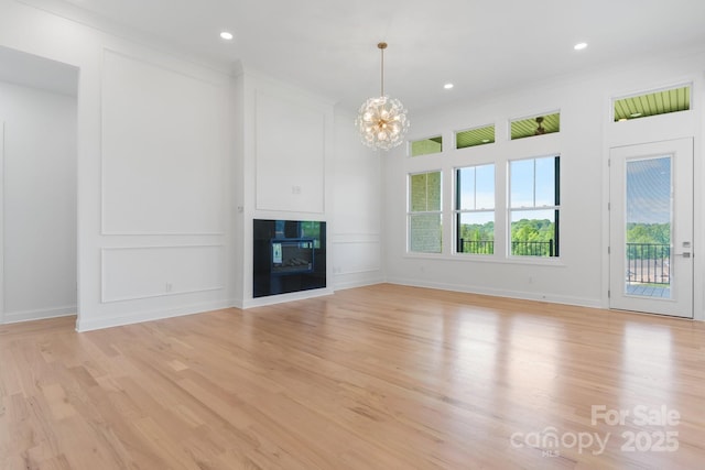 4227 Holly Cir NE, Conover, NC 28613 - unfurnished living room with baseboards, a glass covered fireplace, light wood finished floors, an inviting chandelier, and recessed lighting