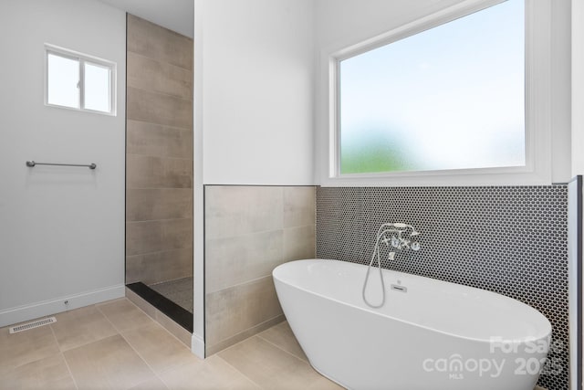 4227 Holly Cir NE, Conover, NC 28613 - bathroom with visible vents, tile patterned flooring, tile walls, a walk in shower, and a soaking tub