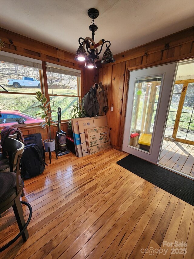 dining area with a wealth of natural light, a notable chandelier, wooden walls, and hardwood / wood-style flooring