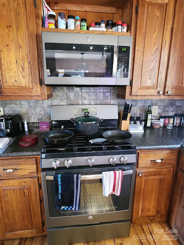 kitchen with stainless steel appliances, brown cabinets, and tasteful backsplash