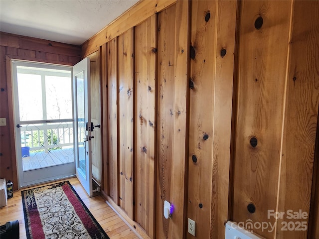 entryway featuring light wood-style floors and wooden walls