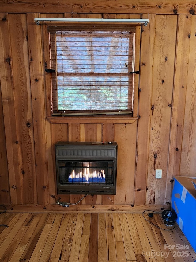 interior details featuring a glass covered fireplace, heating unit, and wood finished floors