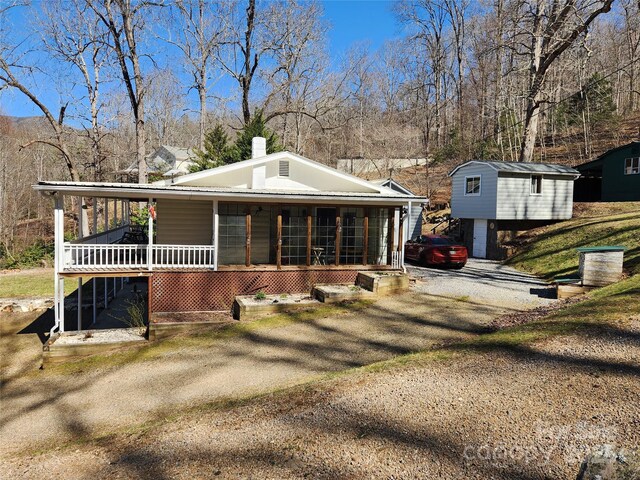 view of front of house featuring metal roof, a porch, and dirt driveway