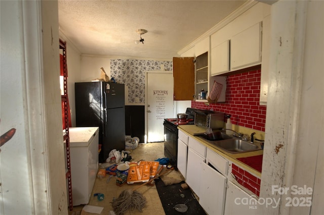 kitchen featuring washer / clothes dryer, a sink, black appliances, white cabinets, and a textured ceiling