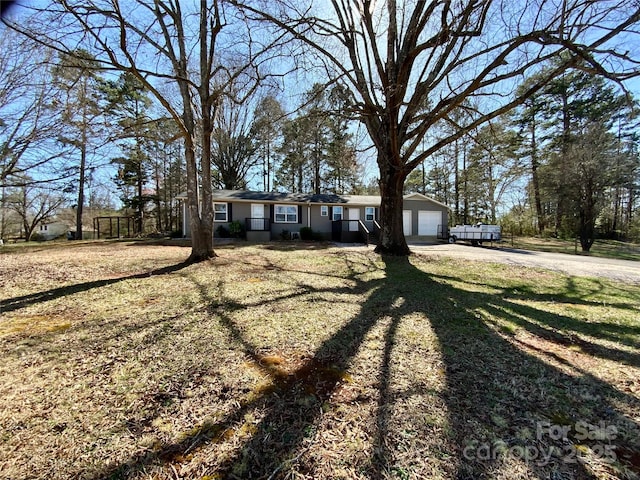 single story home featuring a front lawn, an attached garage, and dirt driveway