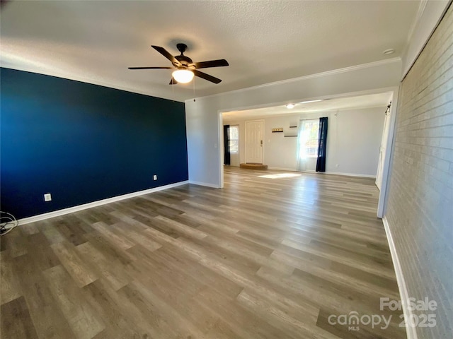 spare room with ceiling fan, baseboards, wood finished floors, and ornamental molding