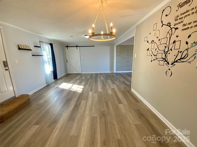 unfurnished dining area with a barn door, baseboards, wood finished floors, and crown molding