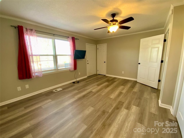 unfurnished bedroom with visible vents, ornamental molding, and wood finished floors