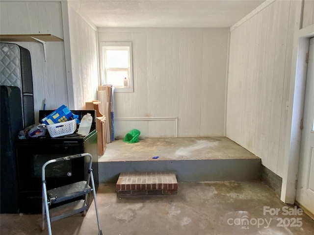 interior space featuring wood walls and unfinished concrete floors