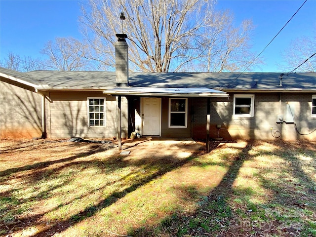 back of house featuring brick siding and a chimney