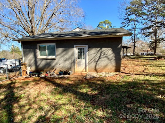 back of property featuring brick siding, a lawn, and fence