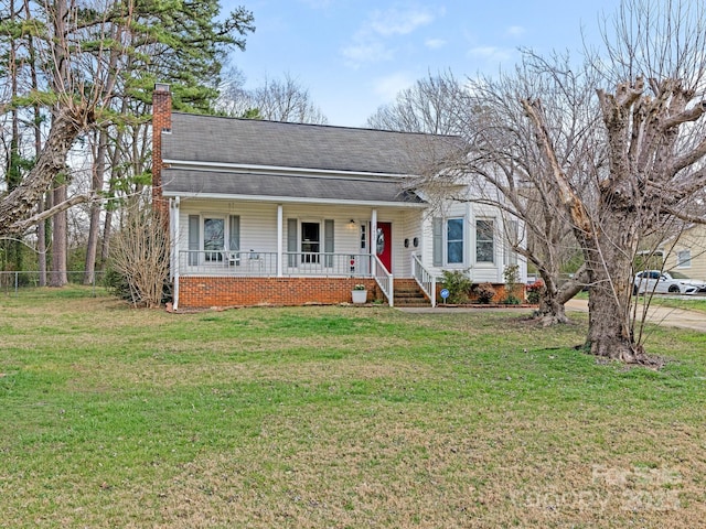 view of front of property with fence, a porch, roof with shingles, a front yard, and a chimney