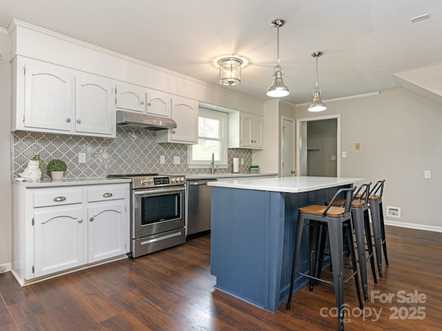 kitchen with under cabinet range hood, appliances with stainless steel finishes, white cabinets, and a center island