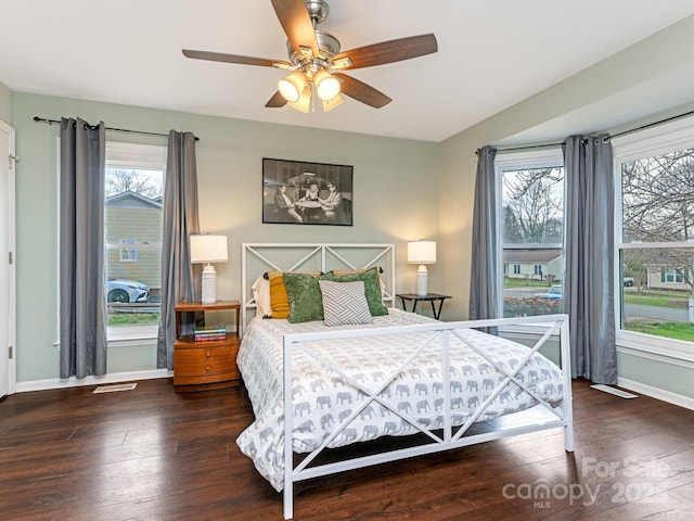 bedroom featuring visible vents, multiple windows, wood finished floors, and baseboards