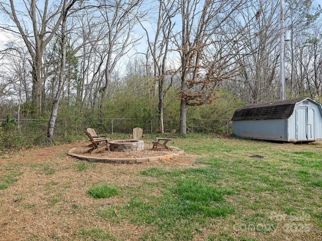 view of yard featuring an outbuilding, a fire pit, a storage shed, and fence