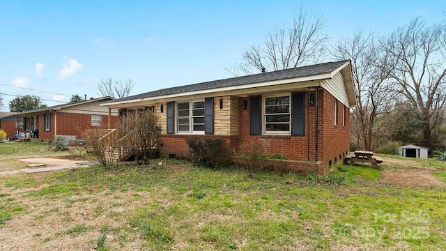 single story home featuring brick siding, an outdoor structure, and a front lawn