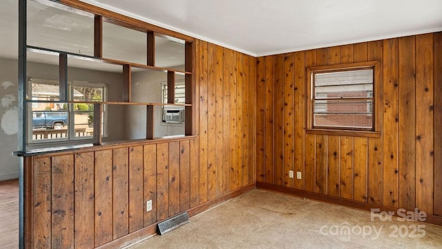 spare room with visible vents, cooling unit, baseboards, and wood walls