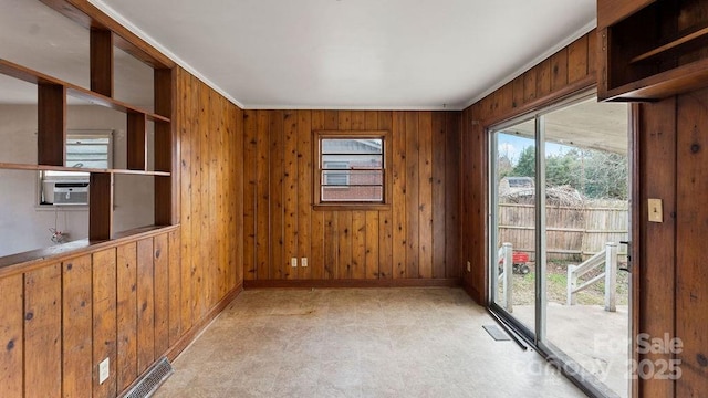 spare room featuring visible vents, wood walls, light floors, and baseboards