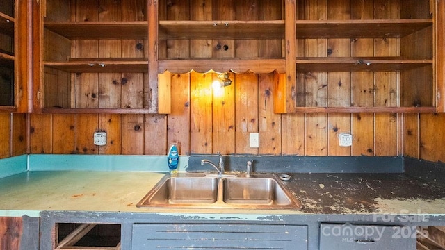 kitchen featuring wood walls, open shelves, and a sink