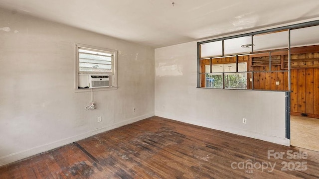 spare room with cooling unit, baseboards, and wood-type flooring