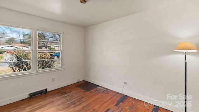 unfurnished room featuring visible vents, baseboards, and wood finished floors