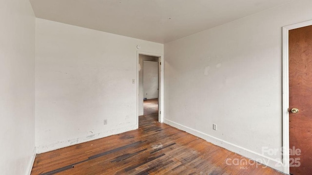 spare room featuring baseboards and wood finished floors