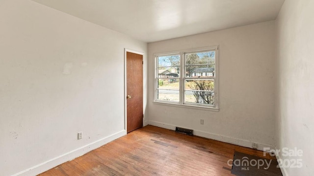 unfurnished room featuring visible vents, light wood-style flooring, and baseboards