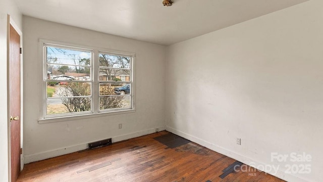 spare room featuring a healthy amount of sunlight, baseboards, and wood finished floors