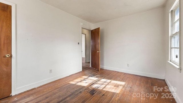 unfurnished room featuring a wealth of natural light, baseboards, and hardwood / wood-style flooring