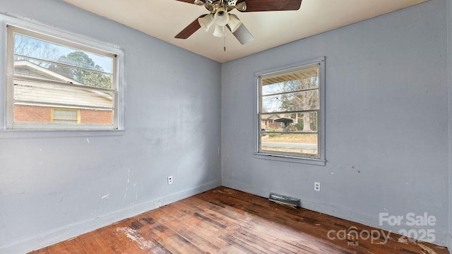 spare room featuring hardwood / wood-style floors, visible vents, baseboards, and a ceiling fan