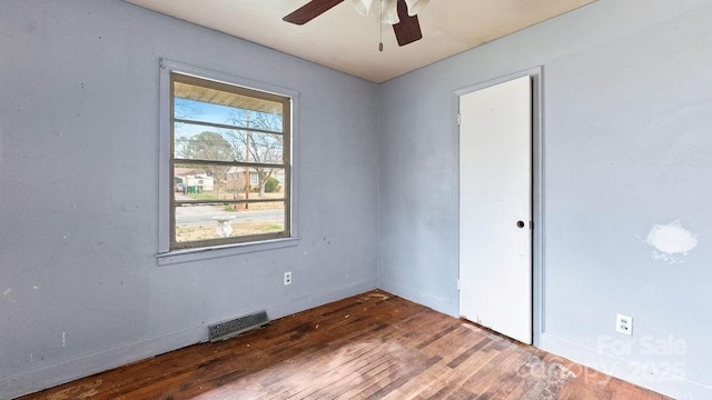 spare room with a ceiling fan, wood finished floors, visible vents, and baseboards