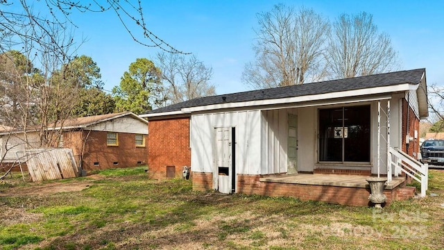 rear view of house featuring crawl space, brick siding, and a yard