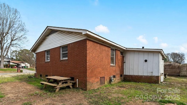 view of property exterior with brick siding and fence