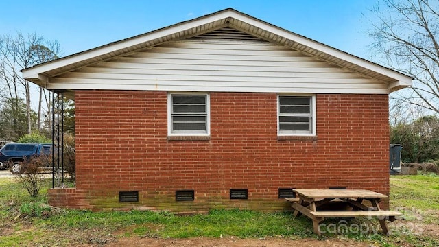 view of side of property featuring crawl space and brick siding