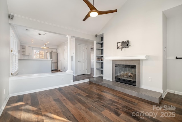 unfurnished living room with dark wood-type flooring, a ceiling fan, a fireplace, decorative columns, and baseboards