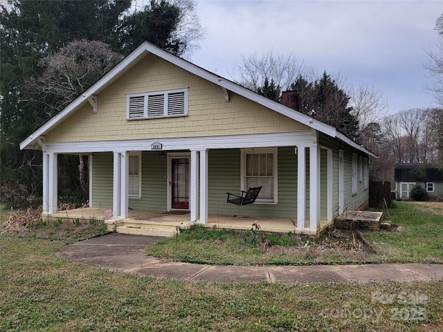 bungalow-style home featuring covered porch and a chimney