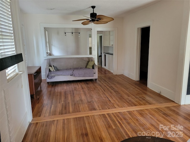 sitting room with ceiling fan, baseboards, and wood finished floors