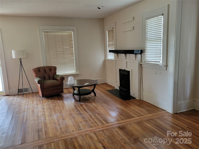 sitting room featuring visible vents, wood-type flooring, baseboards, and a fireplace