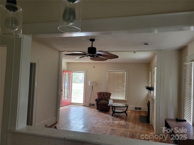 interior space with a ceiling fan, visible vents, wood finished floors, and baseboards