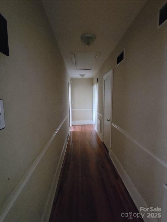 hall with dark wood-style floors, visible vents, and baseboards