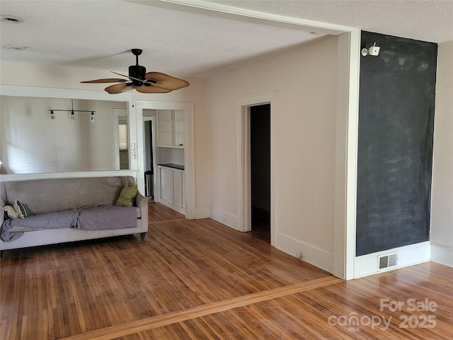 unfurnished living room with visible vents, baseboards, ceiling fan, wood finished floors, and a textured ceiling