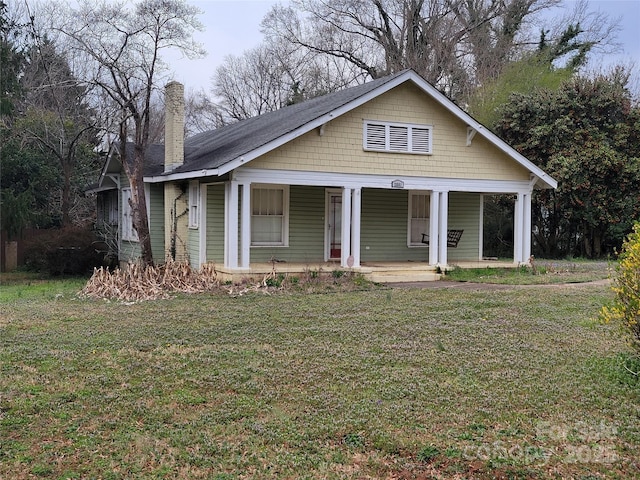 bungalow featuring a front lawn, a porch, and a chimney