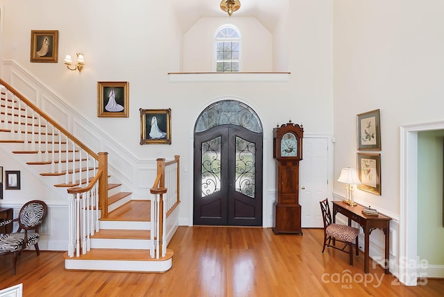 entryway featuring french doors, a high ceiling, wood finished floors, and stairway