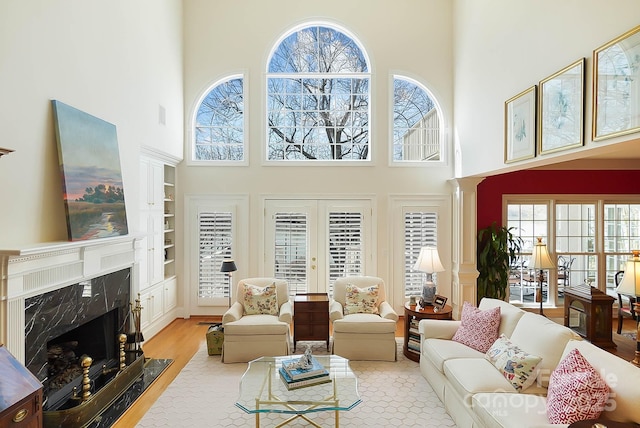 living area featuring a fireplace, wood finished floors, french doors, and a healthy amount of sunlight