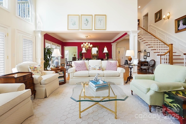 living area featuring a notable chandelier, crown molding, a high ceiling, and decorative columns