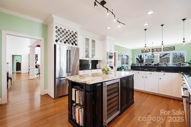 kitchen featuring crown molding, wine cooler, decorative columns, light wood-style flooring, and high end fridge