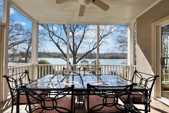 wooden terrace with outdoor dining area, a water view, and a ceiling fan