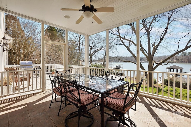 sunroom featuring a ceiling fan, a water view, and a wealth of natural light