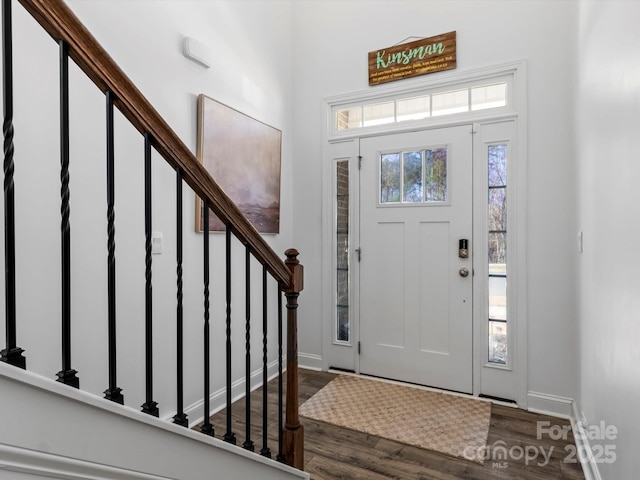 foyer entrance featuring dark wood-style floors, stairway, and baseboards