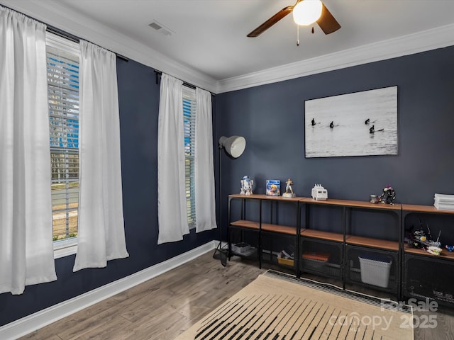 home office featuring wood finished floors, visible vents, baseboards, ceiling fan, and crown molding